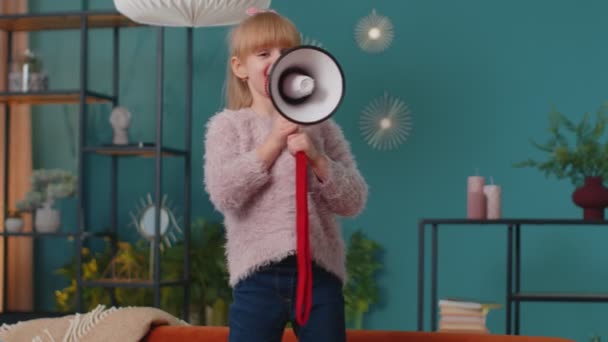 Child girl kid standing on sofa at home alone loudly shout in megaphone announces discounts sale — Stock Video