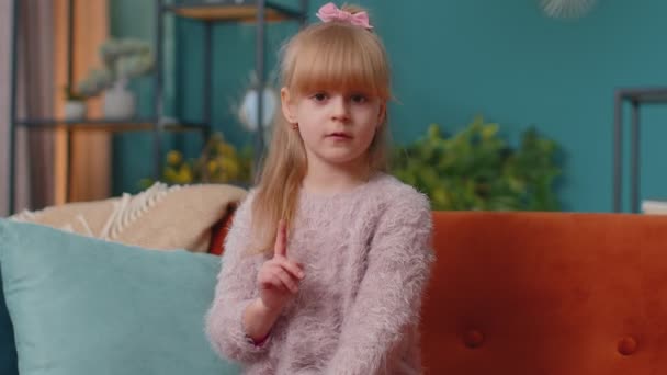 Criança menina garoto sentado no sofá em casa sozinho dizer não segurar palma dobrada mãos cruzadas em gesto stop — Vídeo de Stock