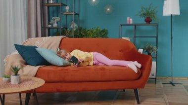 Küçük çocuk akıllı telefonunu tutar çevrimiçi çizgi film izler, evde yalnız başına arkadaşlarıyla sohbet eder.