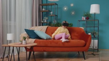 Yeni yürümeye başlayan kız sanal gerçeklik kulaklığı uygulaması kullanarak evde oturuyor. Simülasyon oyunu oynamak için.