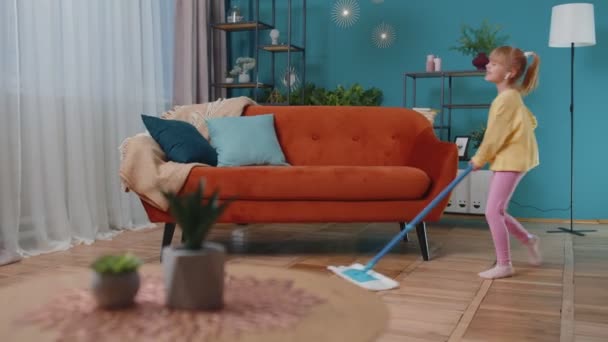 Gyermek lány gyerek lemossa a padlót egy felmosó a háztartási nappali tánc, énekel pozitív hangulatban — Stock videók