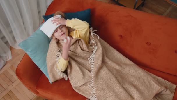 Kind im Karo leidet an Coronavirus oder Allergie, niest Rotz in Serviette auf dem heimischen Sofa — Stockvideo