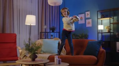 Kulaklıklı mutlu çocuk evde tek başına müzik dinlerken dans ediyor.