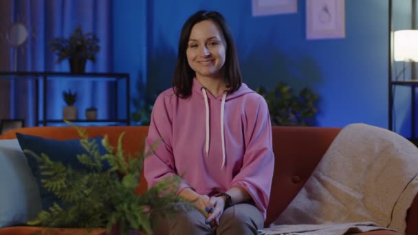 Portrait of happy woman sitting on sofa at home raises thumbs up, likes good, agrees with positive — Stock Video