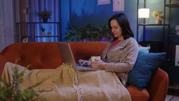 Femme freelance couché sur le canapé, travaillant sur ordinateur portable notebook shopping, étudier en ligne à la maison seul — Video