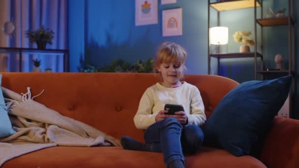 Copil mic ține smartphone vizionarea desene animate amuzante, chat cu prietenii pe canapea singur acasă — Videoclip de stoc