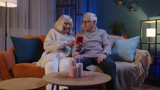 老两口外婆坐在家里的沙发上，用手机上网购物 — 图库视频影像