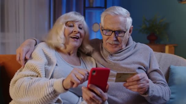 집에 휴대폰을 가지고 있는 할머니와 신용 카드로 온라인 쇼핑을 하는 모습 — 비디오
