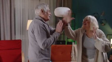 Mutlu son sınıf çifti evde dans ediyor, evde dinleniyor, modern müzikle eğleniyor ve evde gülümsüyor.