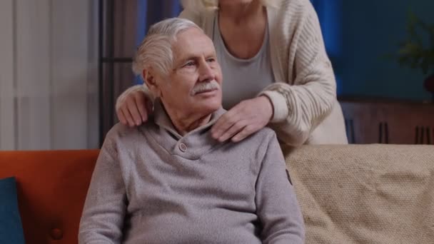 Feliz anciano anciano viejo familia pareja abrazos, sonriendo, sonriendo mirando a la cámara en el sofá de casa — Vídeos de Stock