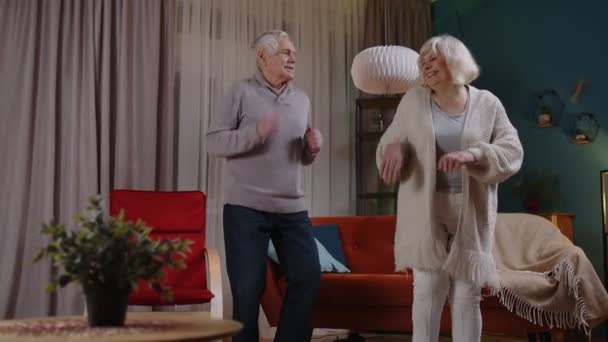 Obekymrade äldre människor par dans hemma koppla av ha kul med modern musik ler hemma — Stockvideo