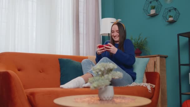 Preocupado engraçado viciado mulher entusiasticamente jogar jogos de corrida de vídeo no telefone móvel em casa — Vídeo de Stock