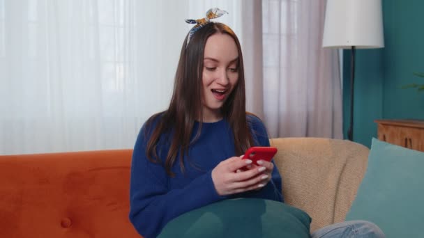 Молода доросла жінка вдома використовує мобільний телефон, друкуючи перегляд скажімо, що вау так виявив велику перемогу — стокове відео
