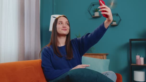 Жінка на дивані вдома з смартфоном, що приймає селфі на мобільний телефон, віртуальний відеодзвінок онлайн — стокове відео
