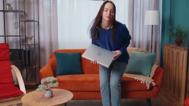 白人の若い女性はソファの上に座っているラップトップPCを開く仕事を開始オンラインで自宅のリビングルームで — ストック動画