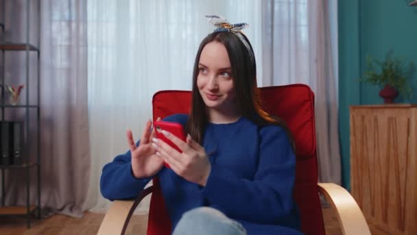 Joyeux jeune femme assise sur la chaise, en utilisant des messages de partage de téléphone mobile sur l'application de médias sociaux — Video