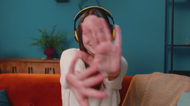 Überglückliche junge Frau mit kabellosen Kopfhörern tanzt, singt auf gemütlicher Couch im heimischen Wohnzimmer — Stockvideo