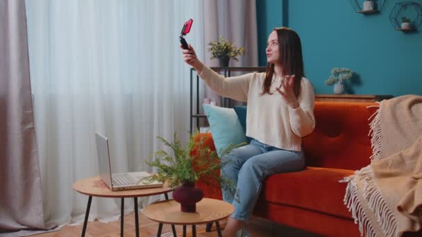 Дівчина-блогер впливає, беручи селфі на смартфон, роблячи віртуальне відео в соціальних мережах онлайн вдома — стокове відео