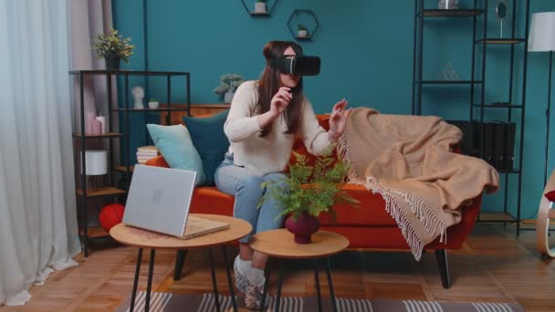 Chica joven usa gafas de auriculares de realidad virtual en casa jugar video juego 3D haciendo gestos con las manos — Vídeos de Stock