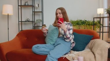 Kadın evde kredi kartı ve akıllı telefon kullanarak para transferi yapıyor.