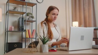 Laptop kullanan genç bir kız. Masada oturuyor, çalışıyor, internetten alışveriş yapıyor.