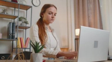 Laptop kullanan genç bir kız masada oturuyor, çalışıyor, klavyede daktilo kullanıyor.