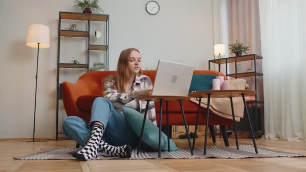 Giovane donna allegra seduta sul pavimento, utilizzando il computer portatile condividere messaggi sull'applicazione di social media — Video Stock