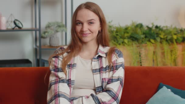 Ritratto di felice una bella adolescente studentessa sorridente, guardando la fotocamera a casa sul divano — Video Stock