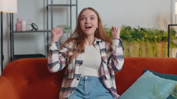 Joven mujer adulta gritando, levantando puños en gesto lo hice, celebrando el éxito, ganando en casa — Vídeos de Stock