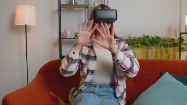 Jovem usa óculos de realidade virtual em casa, desfrutando de conceito de vídeo movendo as mãos no ar — Vídeo de Stock