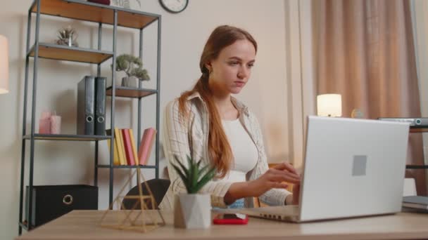 Chica joven usando ordenador portátil sentado en la mesa de trabajo, compras en línea de la oficina en casa — Vídeo de stock