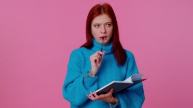 Düşünceli kızıl kadın notlar alıyor, not defterine kalemle düşünceler yazıyor.