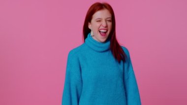 Gülümseyen kızıl saçlı mutlu kız göz kırpıyor, dişlek gülüşüyle kameraya bakıyor, göz kırpıyor ve flört ediyor.