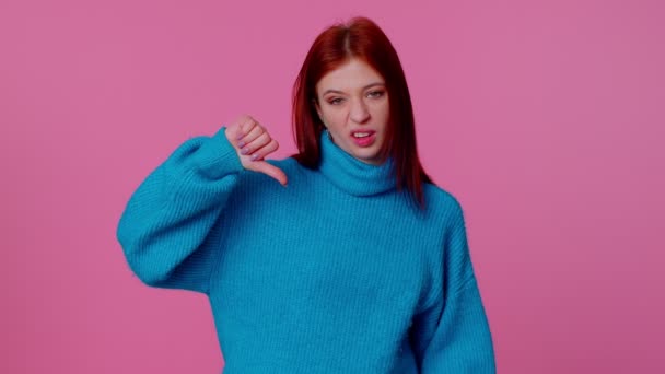 Zdenerwowana dziewczyna w niebieskim swetrze pokazuje kciuki w dół znak gest, dezaprobata, niezadowolony, niechęć — Wideo stockowe