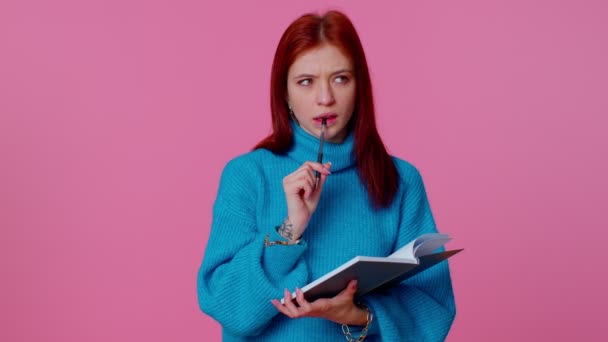 Рыжая женщина делает заметки, записывает мысли ручкой в блокнот дневника — стоковое видео