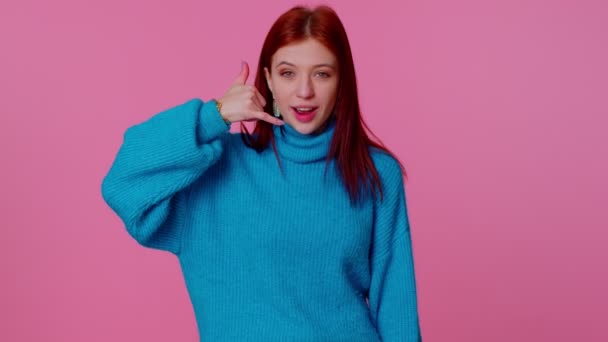 Fröhliches Mädchen im blauen Pullover, das in die Kamera schaut und Handygesten macht, als würde es sagen: "Hallo, du rufst mich zurück" — Stockvideo