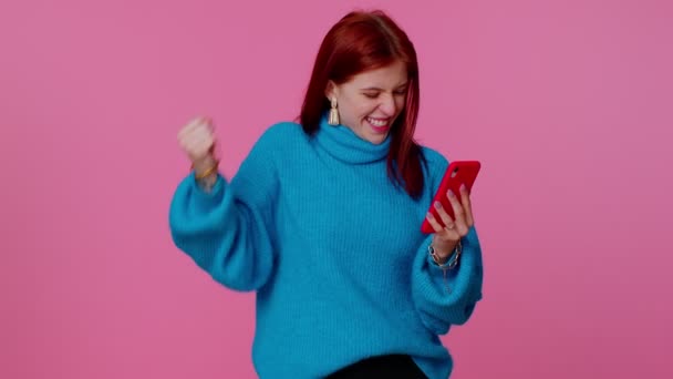 Feliz chica emocionada uso de teléfono móvil decir wow sí se enteró de grandes noticias ganar haciendo gesto ganador — Vídeos de Stock