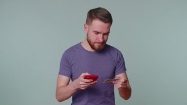 Cep telefonu ve plastik banka kartı kullanan bir adam 