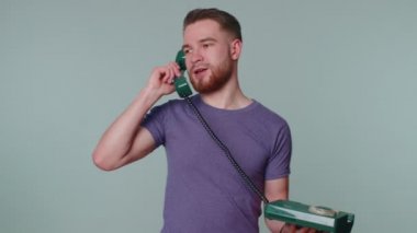 Çılgın, samimi, genç bir adam 80 'lerin klasik telefonundan konuşuyor, aptal aptal, komik suratlar yapıyor.