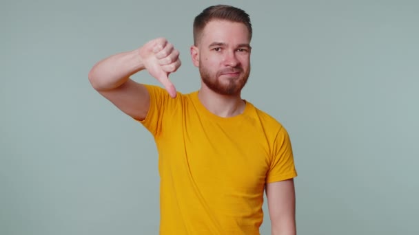 Forstyrret mand i afslappet t-shirt, der viser tommelfingre nedad tegn gestus, misbilligelse, utilfreds modvilje – Stock-video
