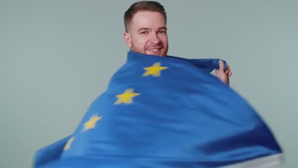 Ember lengeti az Európai Unió zászlaját, mosolyog, éljenzi a demokratikus törvényeket, az emberi jogokat, a szabadságjogokat Európában — Stock videók