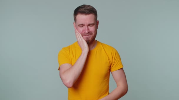 Man touching cheek suffering from toothache cavities or gingivitis waiting for dentist appointment — Stock Video