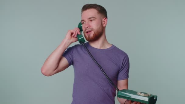 Сумасшедший искренний молодой человек, говорящий по винтажному телефону 80-х, дурачащий, делающий глупые смешные лица — стоковое видео