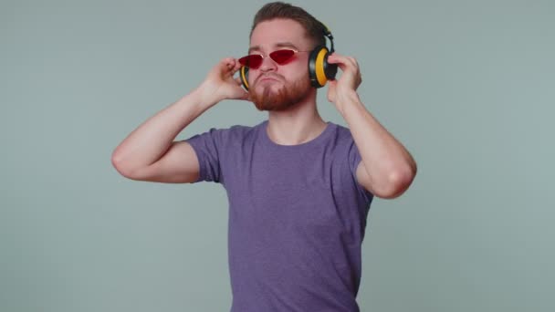 Vrolijke aantrekkelijke man luisteren muziek via koptelefoon en dansen disco gerommel rond plezier hebben — Stockvideo
