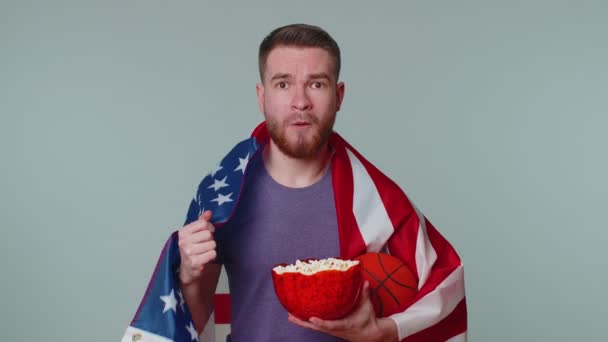 Barbudo joven fanático del baloncesto comiendo palomitas de maíz haciendo gesto ganador, celebrando victoria ganar — Vídeos de Stock