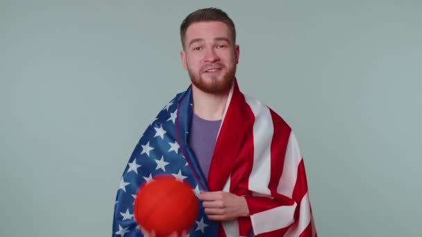 Brodaty młody człowiek kibic koszykówki gospodarstwa amerykańska flaga robi gest zwycięzca, taniec sam — Wideo stockowe