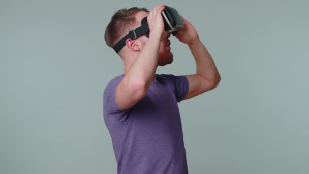 Człowiek wykorzystujący futurystyczną technologię wirtualnej rzeczywistości kask VR do symulacji gry wideo 3D — Wideo stockowe