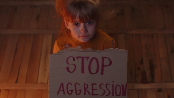 Boję się bezdomnej dziewczynki siedzącej z napisem Stop Agresji, ukrywającej się przed atakiem bombowym. — Wideo stockowe