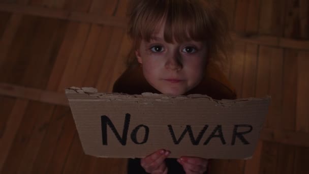 Ängstliches obdachloses Kleinkind sitzt mit der Aufschrift No War und versteckt sich vor Bombenattentat zu Hause — Stockvideo