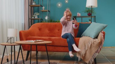 Heyecanlı kazanan kız cep telefonu kullanıyor ve evet diyor evde tek başına sürpriz bir şekilde el kaldırıyor.